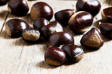 Chestnuts on an old wooden table in the autumn background, selec