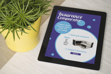 Tablet insurance comparator over a table with plant
