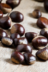 Obraz premium Chestnuts on an old wooden table in the autumn background, selec