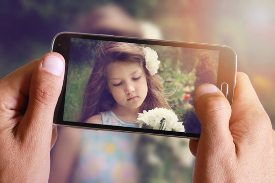 Male hand taking photo of Vintage Portrait of beautiful girl with cell, mobile phone. Kids, childhood, family concept.