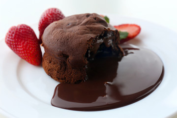 Chocolate fondant with strawberries on white plate, closeup