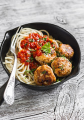 chicken meatballs and spaghetti with tomato sauce in a pan on a dark wooden surface