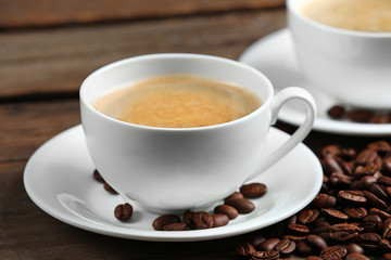 Cups of coffee and beans on wooden table close up