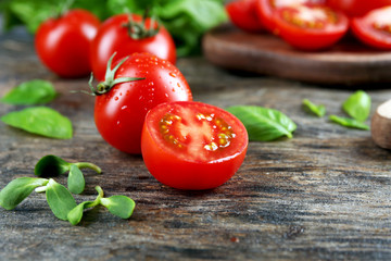 Cherry tomatoes with basil on wooden table close up
