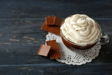 Cup of coffee with cream on color wooden background