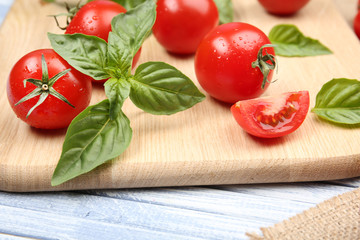 Fresh tomatoes with basil on wooden table close up