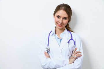 Friendly smiling young female doctor, standing near wall