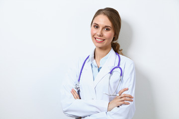 Fototapeta premium Friendly smiling young female doctor, standing near wall