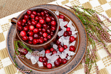 Ceramic cup ,plate with cranberries with sugar crystals on straw napkins,