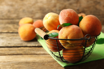 Ripe peaches in basket on wooden background