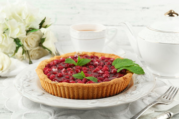 Tart with raspberries and tasty tea, on color  wooden background