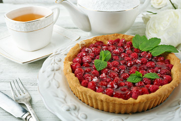 Tart with raspberries and tasty tea, on color  wooden background