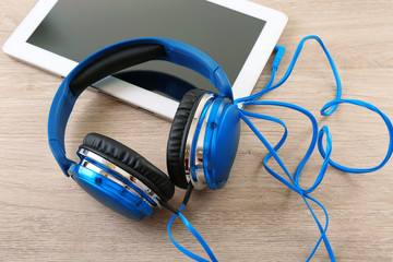 Headphones with tablet on wooden table close up