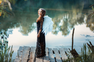 Girl with angel wings standing on the pier and smiling.