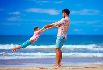 happy excited father and son playing on summer beach, enjoy life