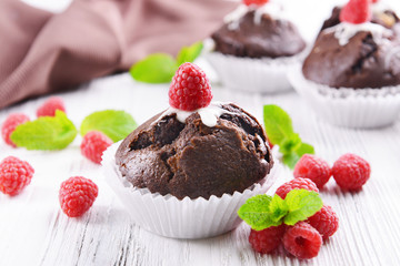 Delicious chocolate cupcakes with berries and fresh mint on table close up