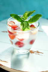 Glass of cold refreshing summer drink with berries and ice cubes on table close up