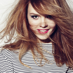 Portrait of a beautiful young girl in a striped t-shirt, smiling in studio, close up