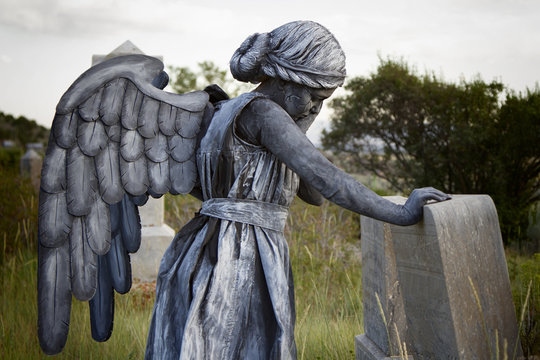 Girl wearing an angel costume in an old grave yard