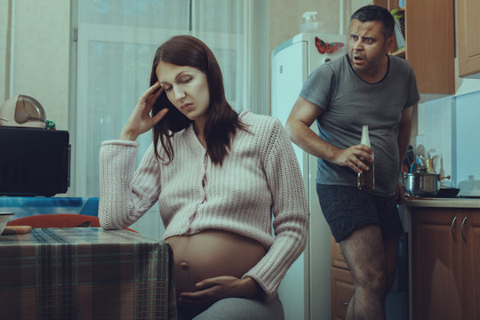 Drunk man with bottle looking at pregnant woman.
