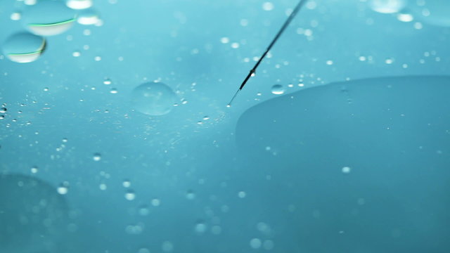 Abstract close-up of floating oil drops and syringe on water surface