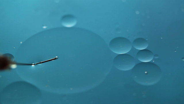 Abstract close-up of floating oil drops and syringe and blood on water surface