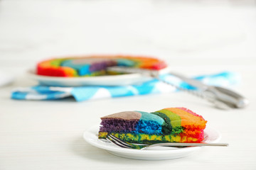 Delicious rainbow cake on plate, on  light background