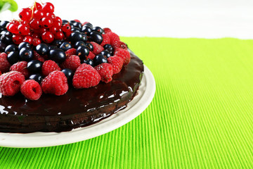 Delicious chocolate cake with summer berries on green tablecloth, closeup