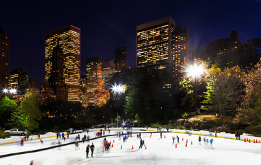 New York City ice rink at night surrounded by skyscrapers