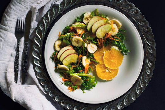 Plate of healthy green garden salad with fresh vegetables, apple, orange and banana 