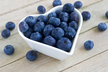  Fresh blueberries in heart-shaped white bowl.