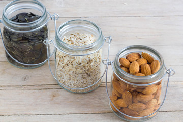 Different healthy nuts in a jar on a wooden table.