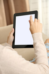 Female hand holding PC tablet on home interior background