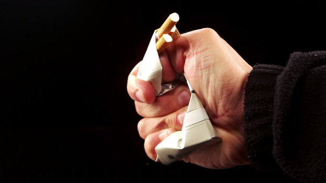 Hand squashing a pack of cigarettes