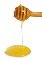 Honey dripping from dipper on light surface