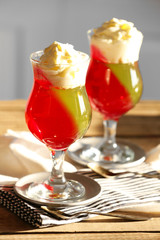 Tasty Jelly desserts with cream on light background