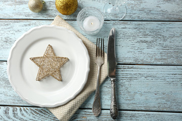 Empty plate, cutlery, napkin and glass on rustic wooden background. Christmas table setting concept
