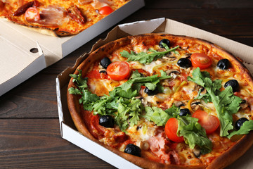 Pizza in box on wooden table closeup