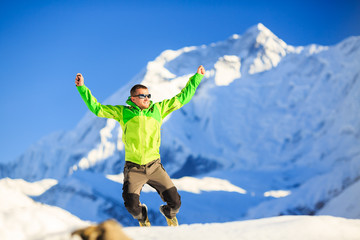 Man hiker accomplish happy jump in winter mountains Himalayas, Nepal