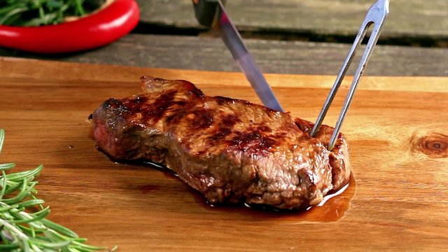 Slicing of grilled steak on a cutting board