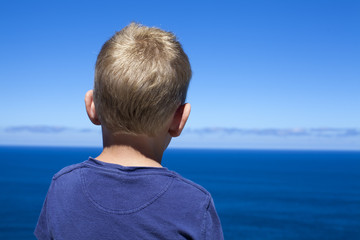 Niño rubio mirando el mar