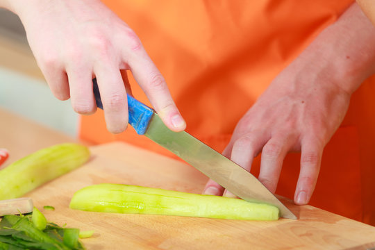 man preparing vegetables salad slicing cucumber