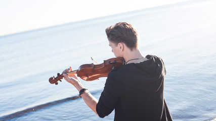 Violinist playing a violin,  young man plays on the background © Ulia Koltyrina