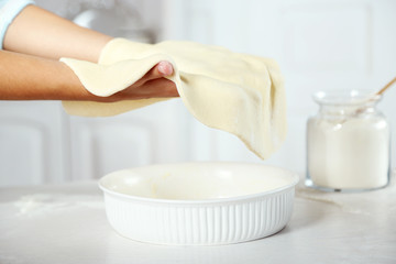 Woman making pie on wooden table, on light background