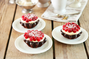 Sweet cakes with raspberries on light wooden background
