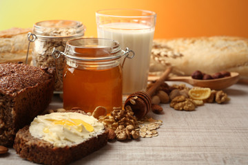 Healthy breakfast with bread, honey, nuts on table, on colorful background. Country breakfast concept