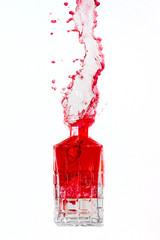 Crystal bottle with liquid splashing out on a white background