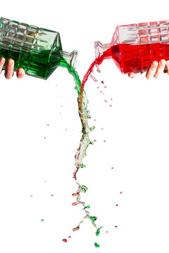 Crystal bottles pouring red and green liquid against a white background