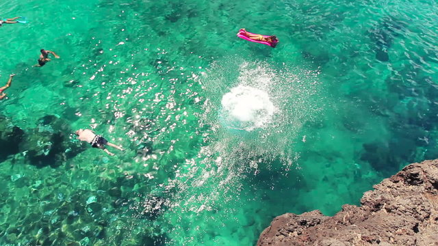 Beautiful Girl Jumps Off Cliff into Ocean in Bikini in Hawaii. Summer Outdoor Lifestyle.