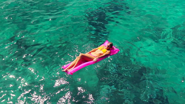 Beautiful Young Blonde Women In Bikini Floating on Pink Inflatable Raft in Crystal Ocean in Hawaii. Summer Fun Vacation Lifestyle. 